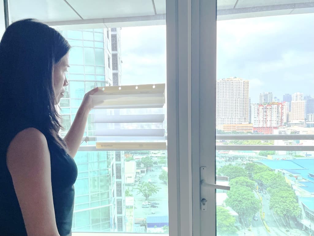 Window covering design consultant holding a sample on a window during in-home consultation